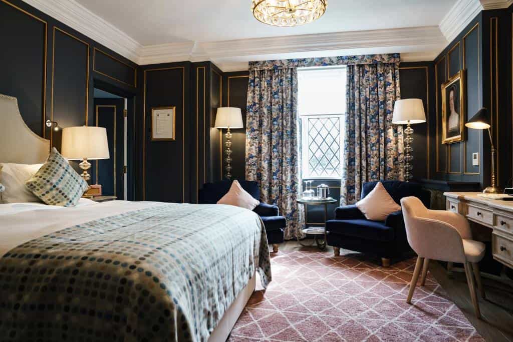 Luxurious hotel bedroom with dark paneled walls, patterned curtains, and a large bed.