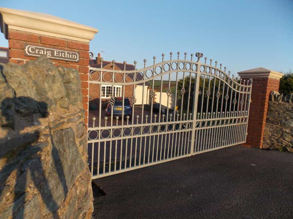 Wrought iron gate for Craig Eithin B&B entrance with brick pillars and stone wall.