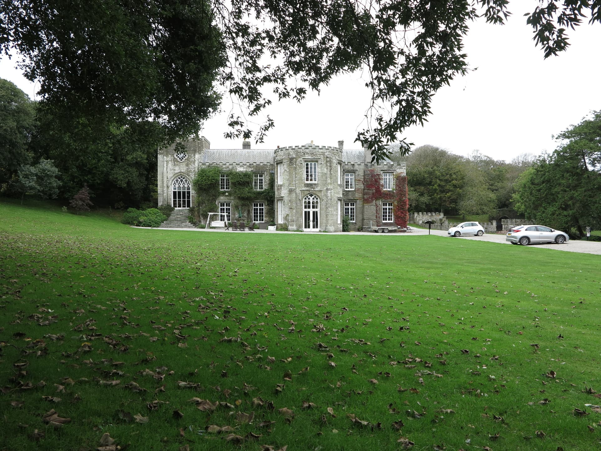 Stone country house with large lawn scattered with autumn leaves, Padstow Palace.
