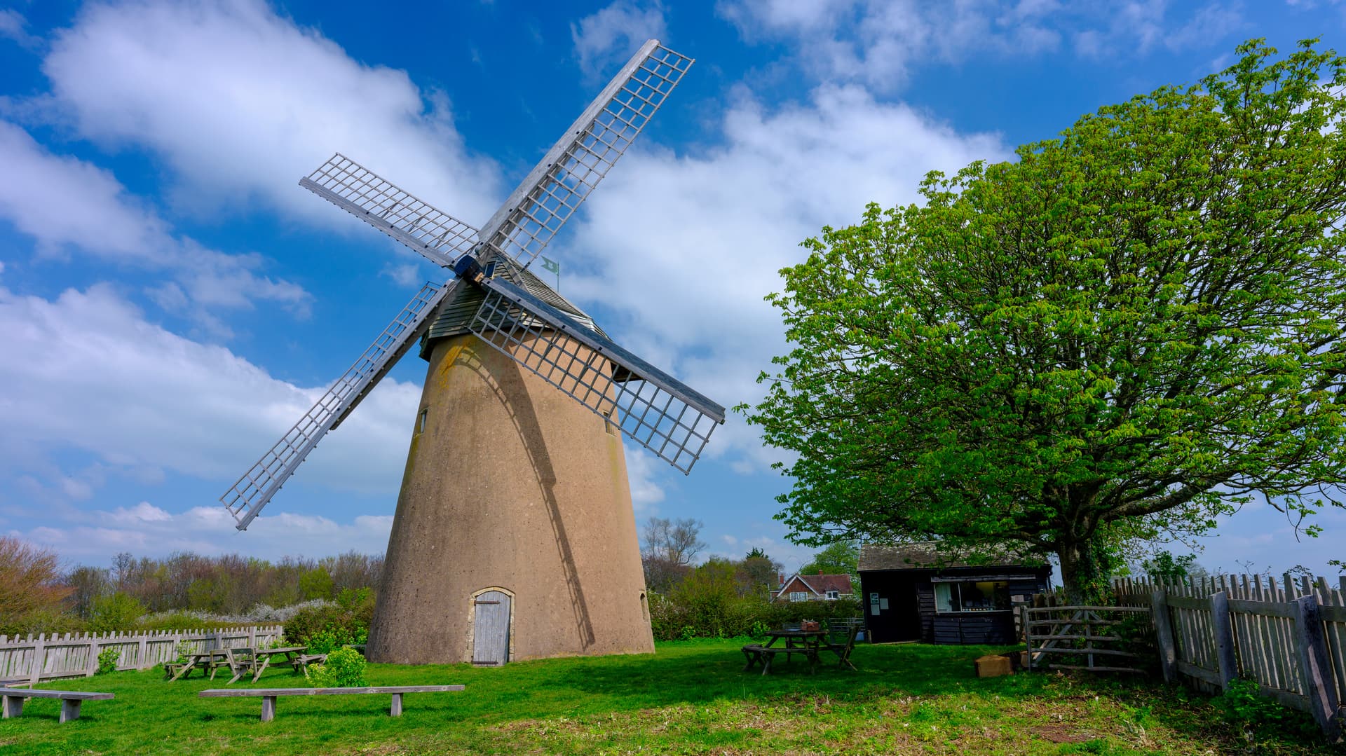 Historic windmill with sails against a bright blue sky with white clouds, Bembridge.
