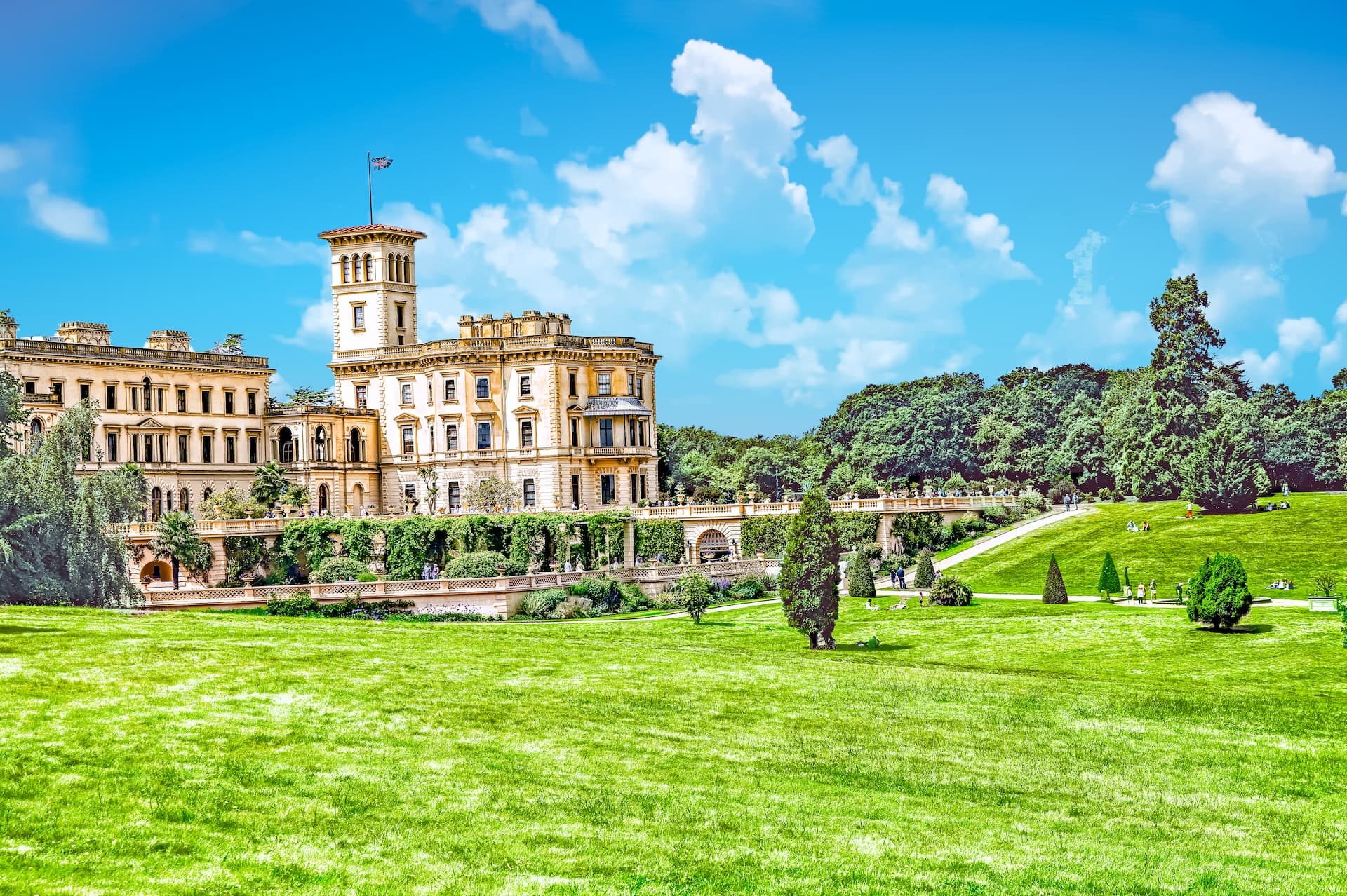 Osborne House with Italianate architecture overlooking a large green lawn under a blue sky.