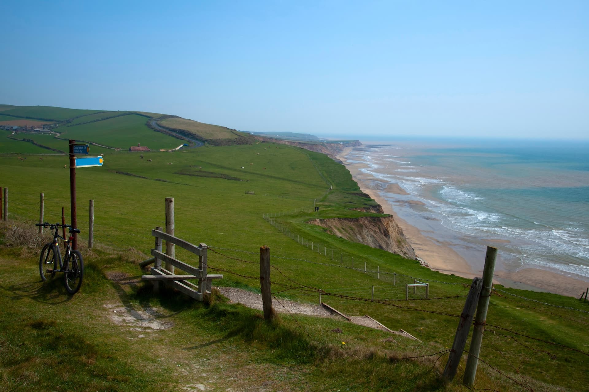 Bicycle parked by footpath sign overlooking Isle of Wight chalk cliffs and beach.