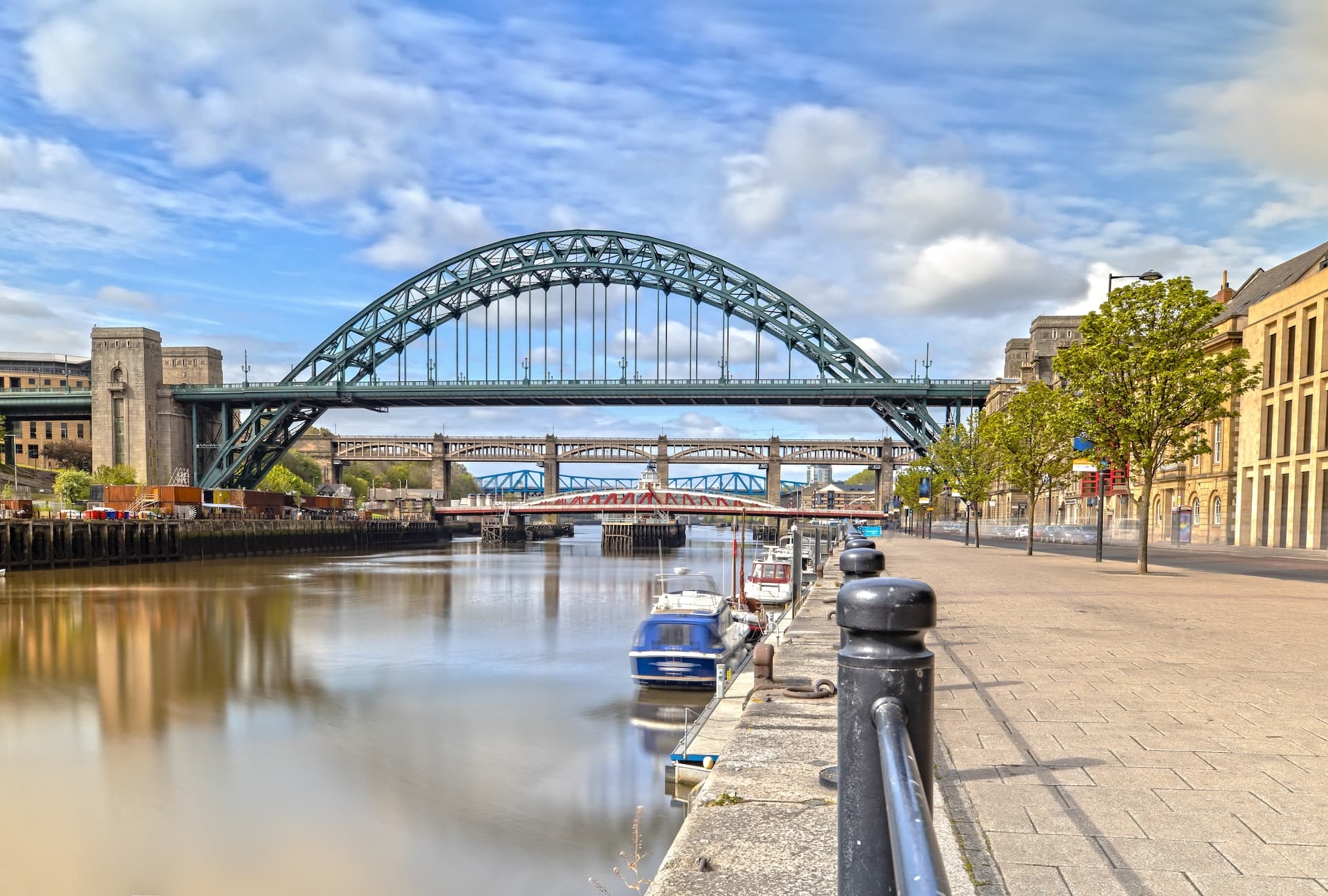 Tyne Bridge and multiple other bridges over the River Tyne with moored boats.