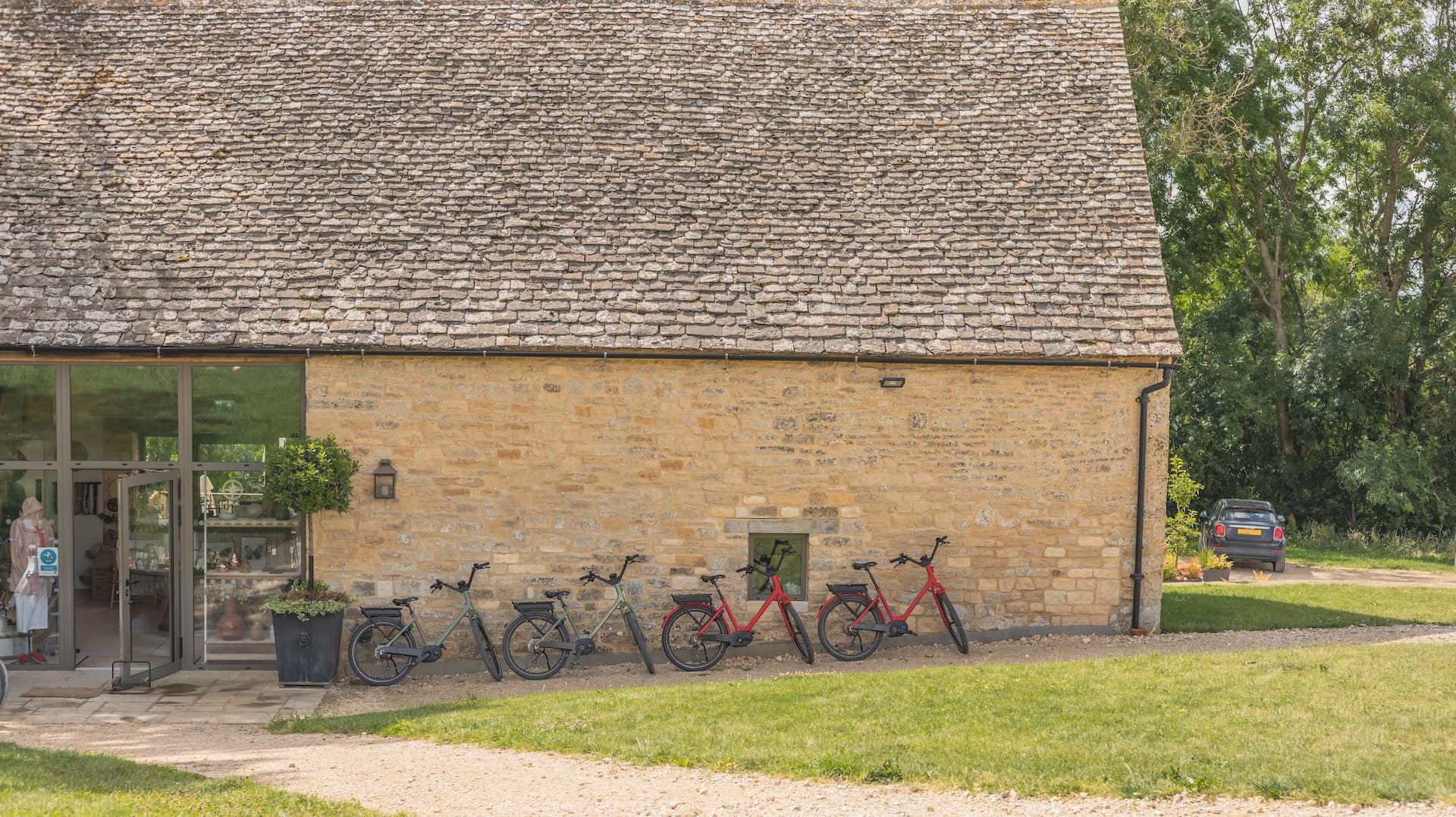 Bikes parked outside Cotswolds stone building with slate roof and glass entrance