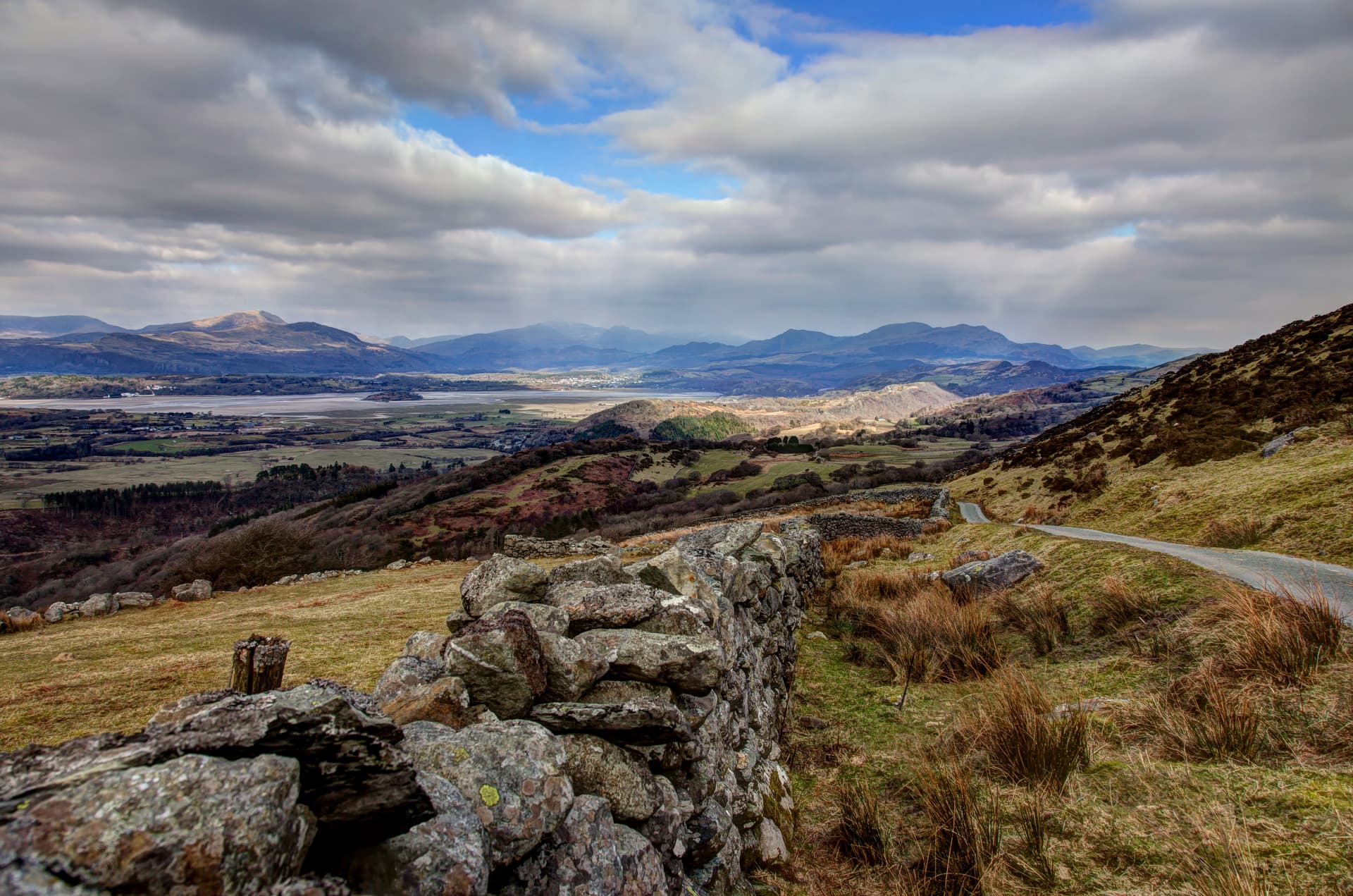 Stone wall beside road overlooking valley, estuary, and mountains near Porthmadog.