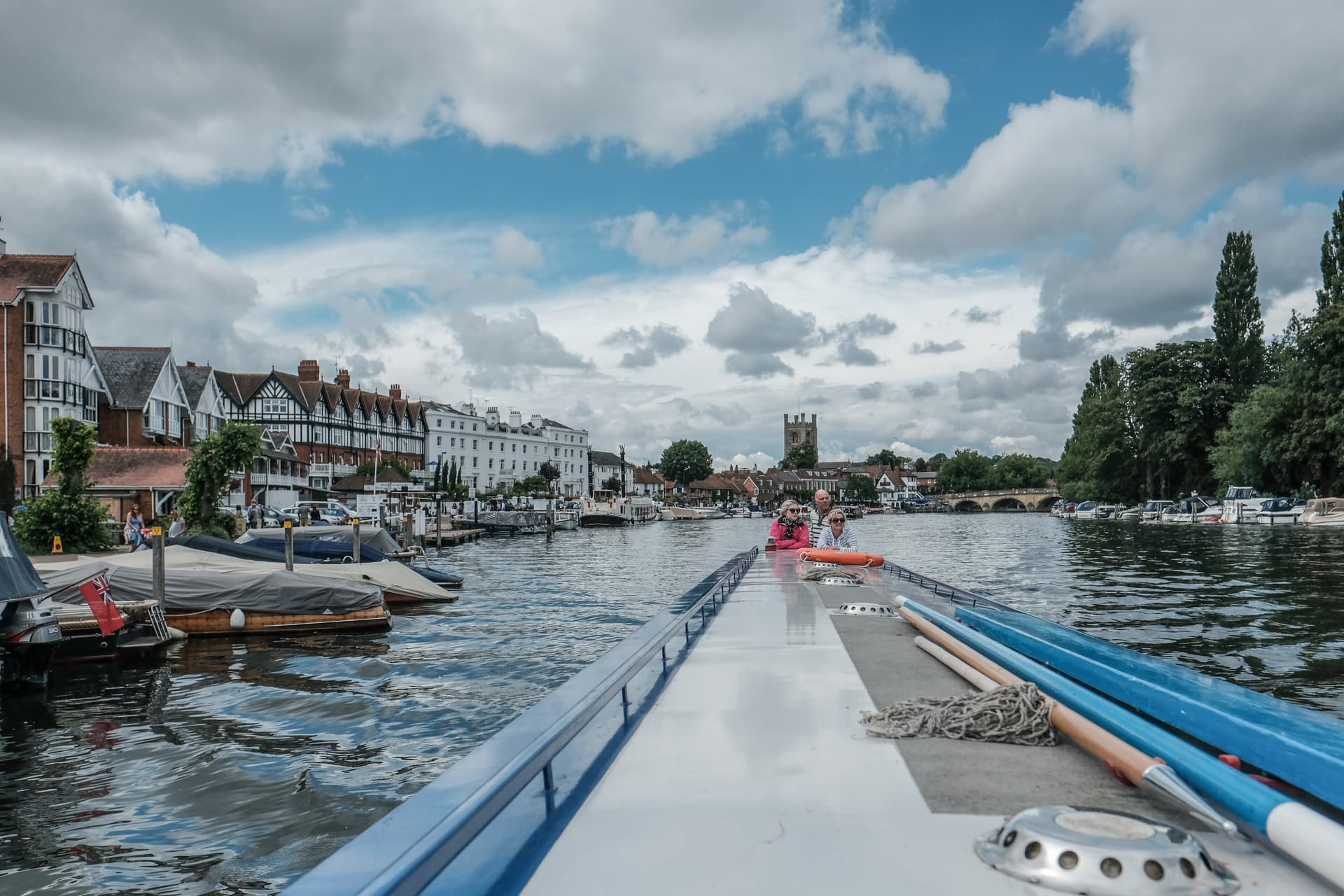 Boat traveling on river toward Henley-on-Thames town with historic buildings and bridge.