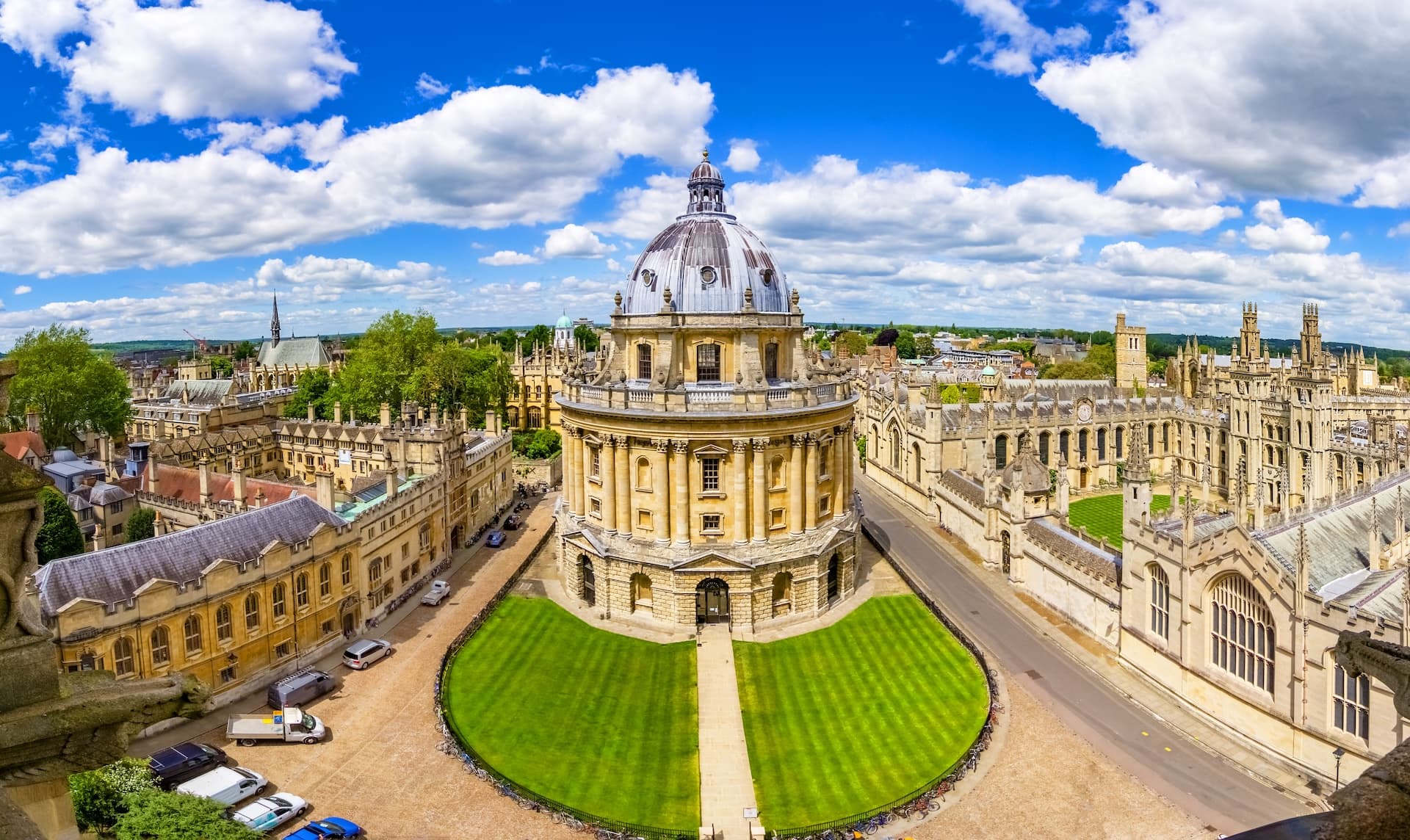 Radcliffe Camera dome surrounded by historic university buildings in Oxford under a bright blue sky.