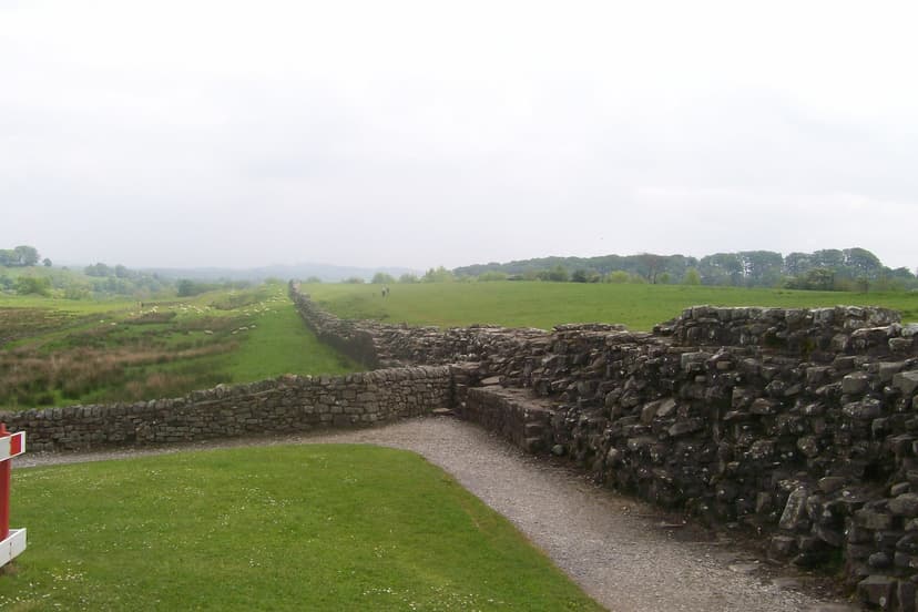 Historic stone wall crossing rolling green fields at Birdoswald Roman Fort on Hadrian's Wall