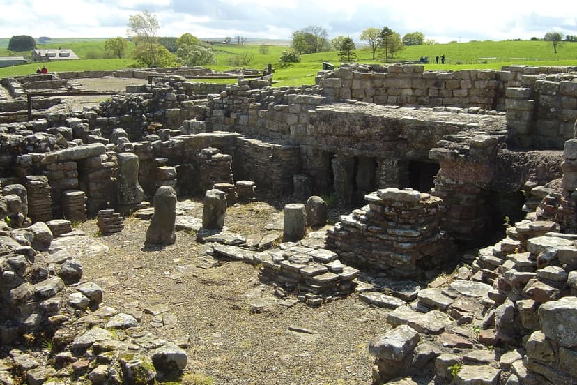 Vindolanda Roman bath house stone ruins with hypocaust pillars and green rolling hills in background