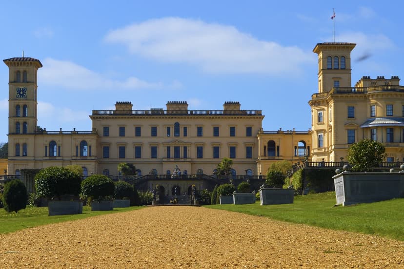 Osborne House yellow facade and clock tower with gravel path and lawn in foreground