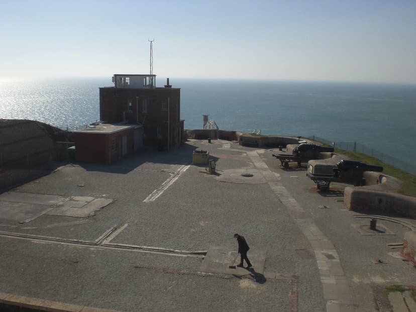 Person sweeping courtyard at Needles Old Battery overlooking the sea